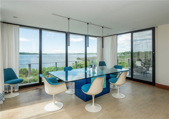 dining space with a water view, floor to ceiling windows, and a wealth of natural light