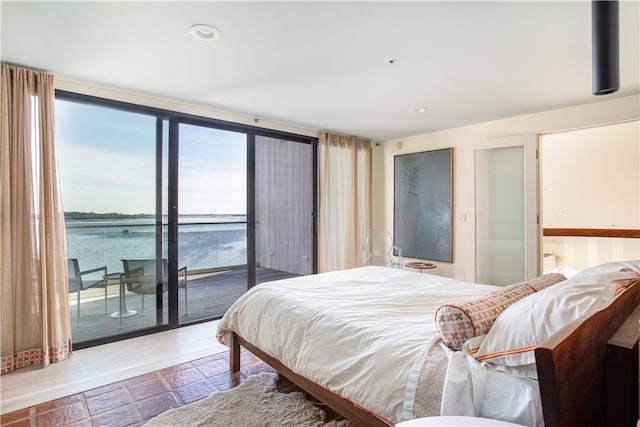 bedroom featuring floor to ceiling windows, a water view, access to exterior, and multiple windows