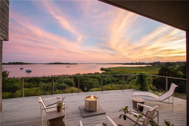 deck at dusk featuring a water view