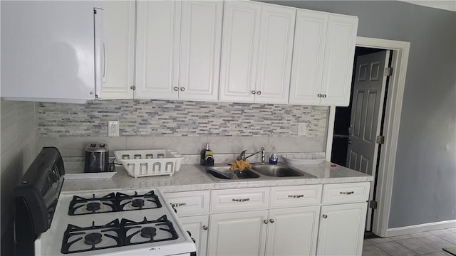 kitchen featuring tasteful backsplash, white gas range, sink, light tile patterned floors, and white cabinets