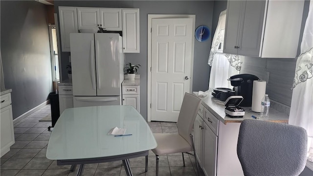 kitchen with tile patterned floors, white refrigerator, white cabinetry, and tasteful backsplash