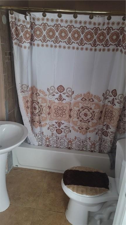 bathroom with tile patterned floors, toilet, and shower / bath combo with shower curtain