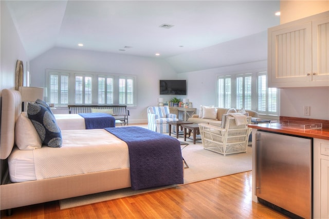 bedroom featuring light wood-type flooring, vaulted ceiling, and multiple windows