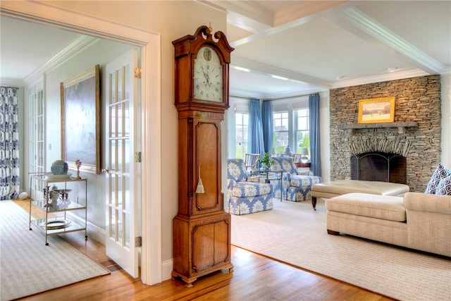 living room featuring crown molding, a stone fireplace, and wood-type flooring