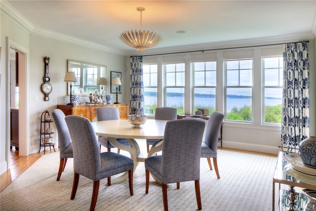 dining area with crown molding, plenty of natural light, an inviting chandelier, and a water view