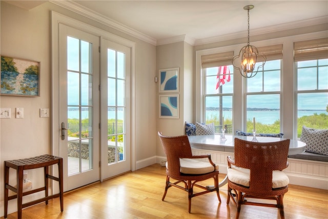 dining space with light hardwood / wood-style flooring, crown molding, a water view, and an inviting chandelier