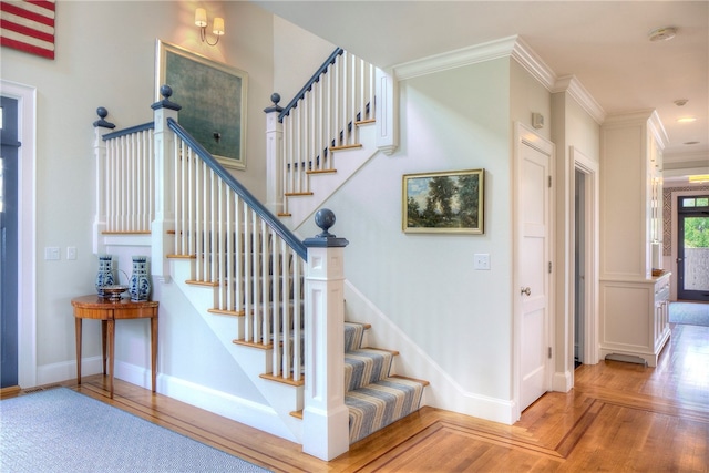 stairway with hardwood / wood-style flooring and ornamental molding