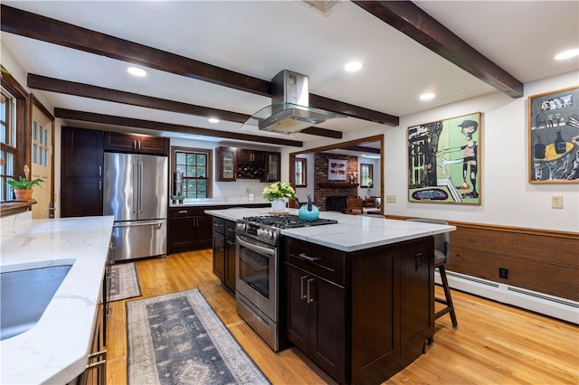 kitchen featuring stainless steel appliances, light hardwood / wood-style floors, light stone counters, island exhaust hood, and a kitchen island