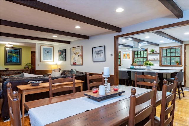 dining area with beam ceiling and light hardwood / wood-style floors