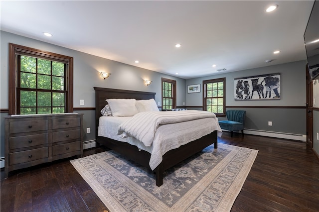 bedroom featuring multiple windows, a baseboard heating unit, and dark hardwood / wood-style floors