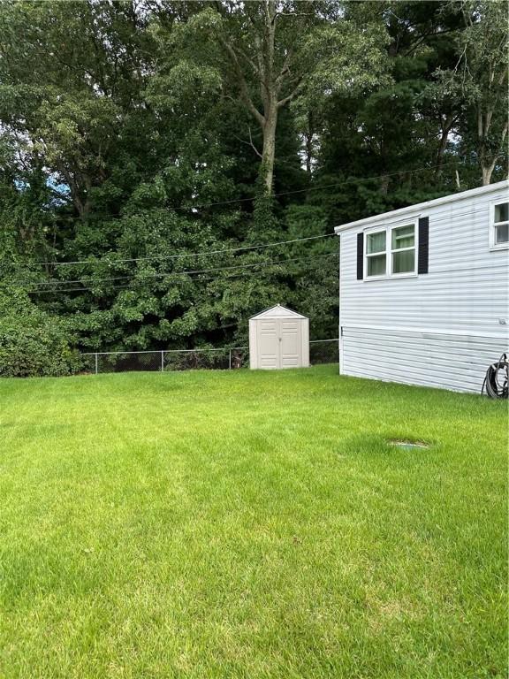 view of yard featuring an outbuilding, fence, and a storage shed