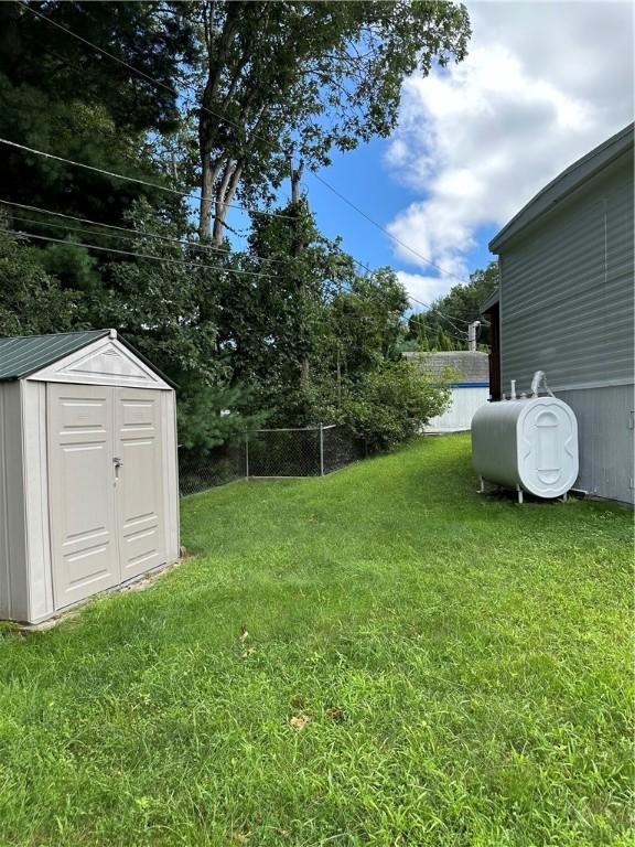 view of yard featuring an outdoor structure, fence, heating fuel, and a shed