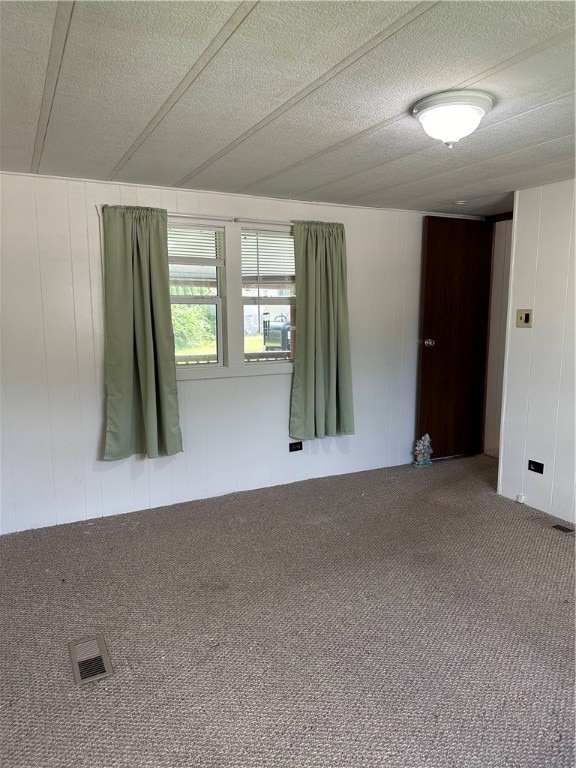 spare room featuring carpet floors and a textured ceiling