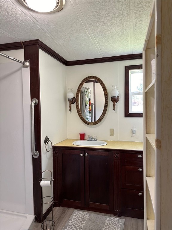 bathroom with a textured ceiling, vanity, and wood-type flooring