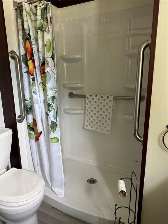 bathroom with hardwood / wood-style flooring, toilet, and walk in shower