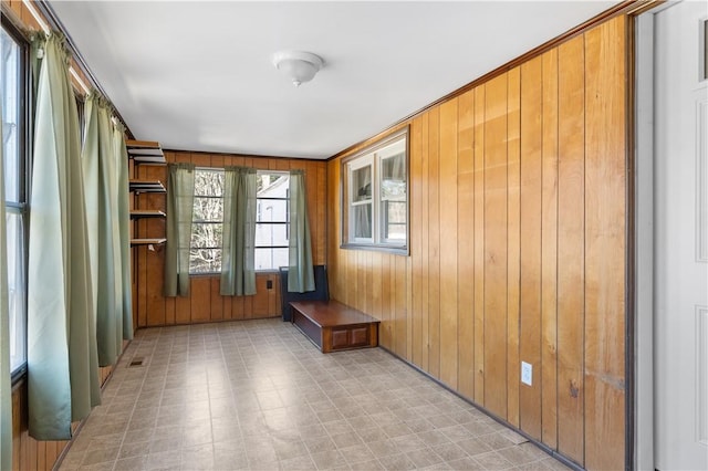 unfurnished room featuring visible vents, wood walls, and light floors