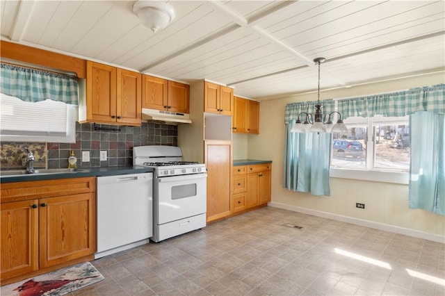 kitchen featuring under cabinet range hood, white appliances, a sink, decorative backsplash, and dark countertops