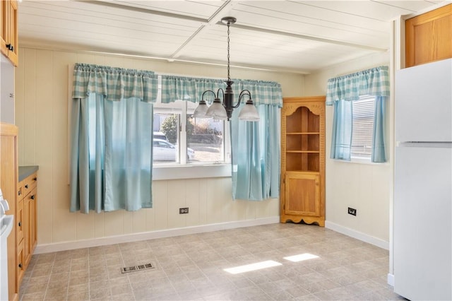 unfurnished dining area with baseboards, visible vents, and a notable chandelier