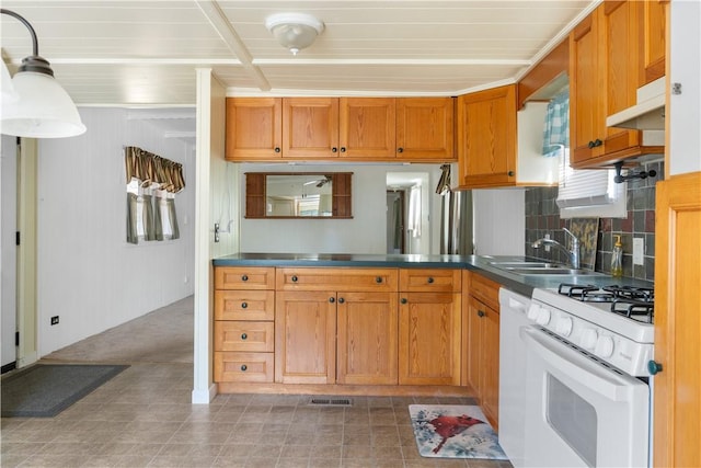 kitchen with white appliances, brown cabinetry, a sink, and under cabinet range hood