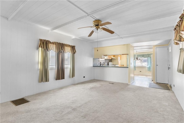 unfurnished living room featuring a ceiling fan, visible vents, carpet flooring, and beamed ceiling