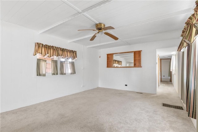 carpeted spare room featuring ceiling fan, visible vents, and beam ceiling