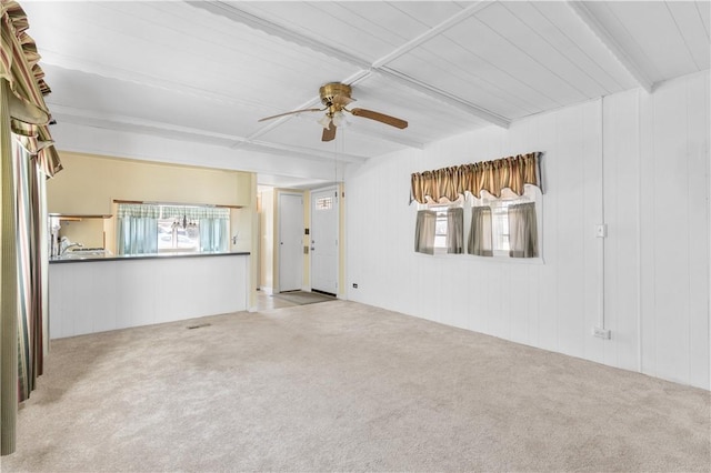 unfurnished living room with carpet floors, beam ceiling, and a ceiling fan