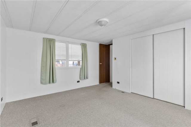 unfurnished bedroom with a closet, visible vents, and carpet flooring