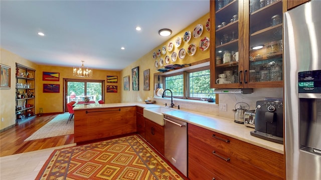 kitchen featuring stainless steel appliances, decorative light fixtures, hardwood / wood-style floors, sink, and kitchen peninsula