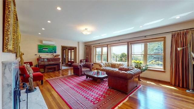 living room with a fireplace, light hardwood / wood-style flooring, and a wall mounted AC