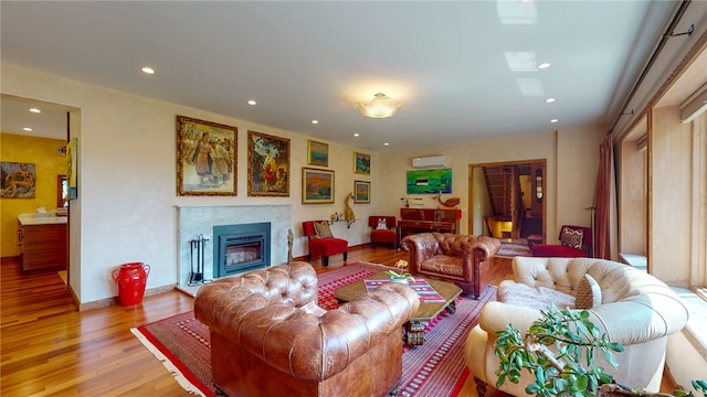 living room with hardwood / wood-style floors, a wall mounted air conditioner, and a fireplace