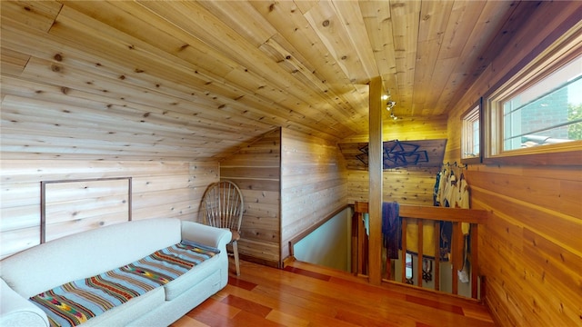 bedroom with wood walls, vaulted ceiling, hardwood / wood-style flooring, and wooden ceiling