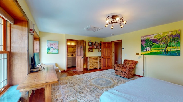 bedroom with hardwood / wood-style floors and connected bathroom