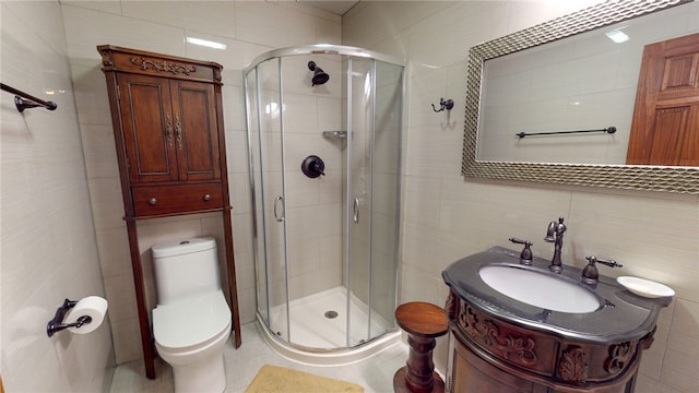 bathroom with tile walls, a shower with door, vanity, and toilet