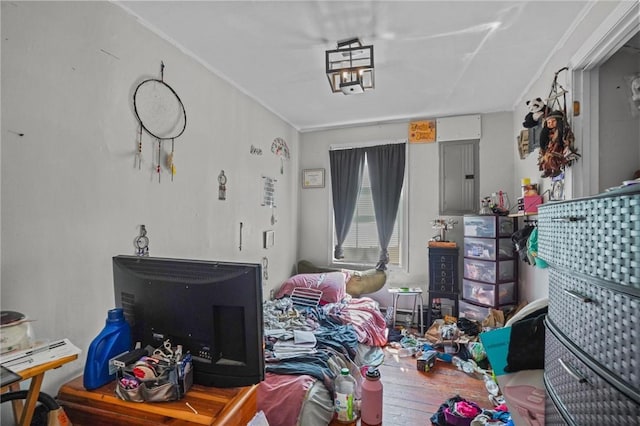 bedroom featuring ornamental molding, wood finished floors, and electric panel