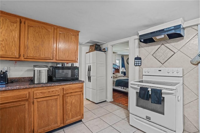 kitchen featuring white electric range oven, dark countertops, extractor fan, black microwave, and light tile patterned flooring