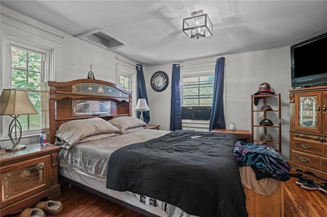 bedroom featuring attic access, multiple windows, and dark wood-type flooring