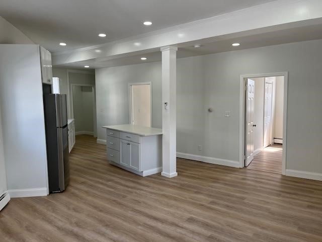 spare room with light hardwood / wood-style flooring, a baseboard radiator, and decorative columns