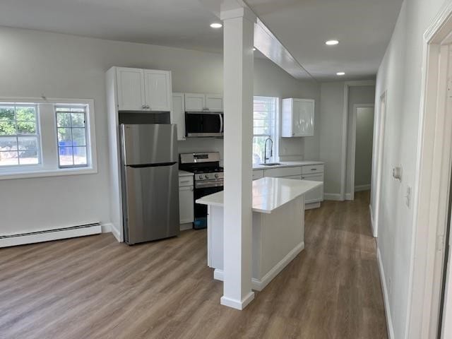 kitchen with white cabinetry, a baseboard heating unit, light hardwood / wood-style floors, and stainless steel appliances