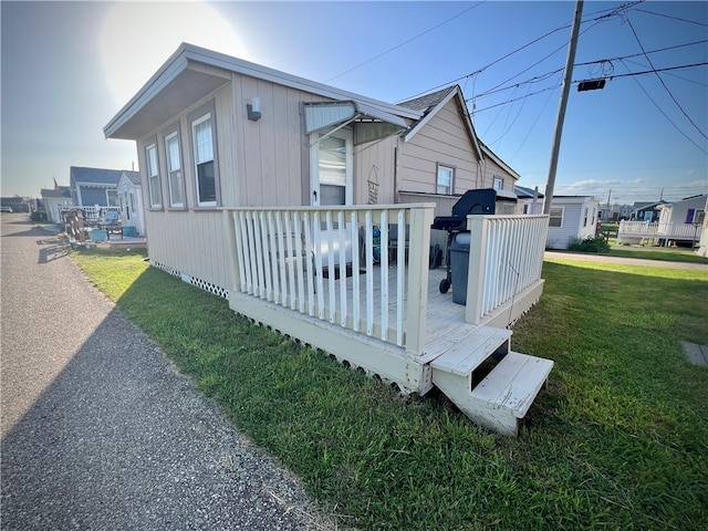 view of side of property featuring a wooden deck and a lawn