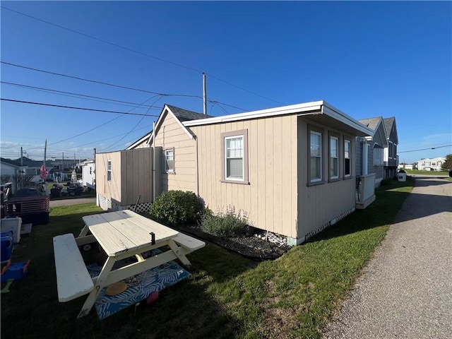 view of side of home featuring a residential view, roof with shingles, and a yard