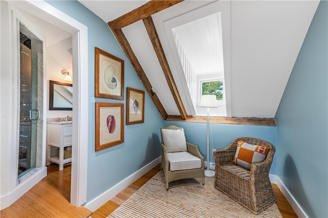 living area with sink, light hardwood / wood-style flooring, and vaulted ceiling with beams