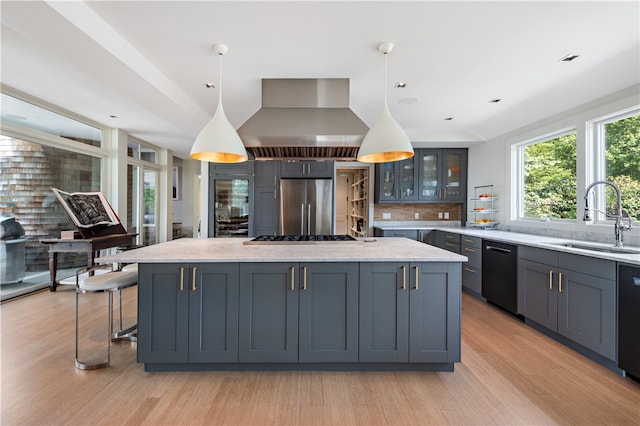 kitchen featuring tasteful backsplash, appliances with stainless steel finishes, extractor fan, decorative light fixtures, and sink