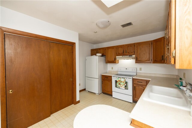 kitchen with light tile patterned floors, sink, a skylight, and white appliances