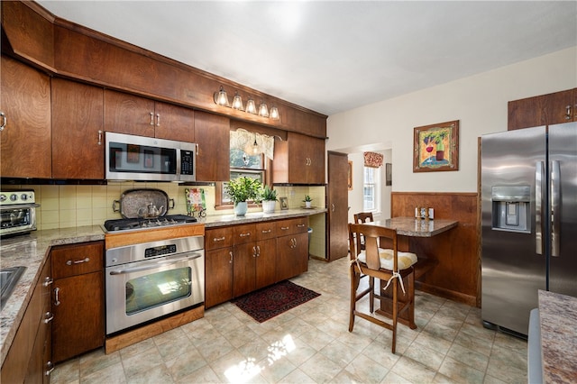 kitchen with stainless steel appliances, decorative backsplash, and stone countertops