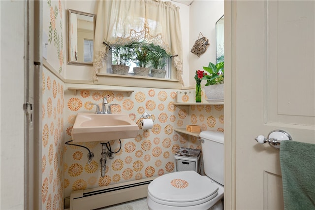 bathroom featuring a baseboard heating unit, toilet, and sink