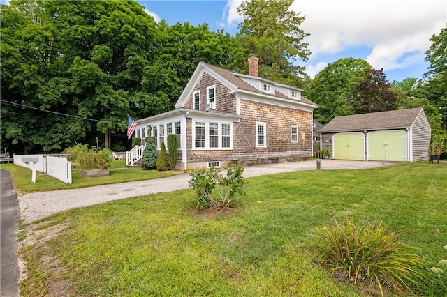 view of front of home featuring an outdoor structure, a garage, and a front lawn