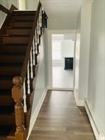 stairs with a baseboard heating unit and wood-type flooring