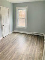 unfurnished room with a baseboard heating unit and light hardwood / wood-style flooring