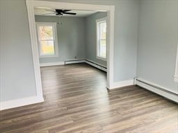 spare room with wood-type flooring, baseboard heating, and ceiling fan