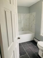 bathroom with tiled shower / bath, toilet, a baseboard heating unit, and tile patterned flooring